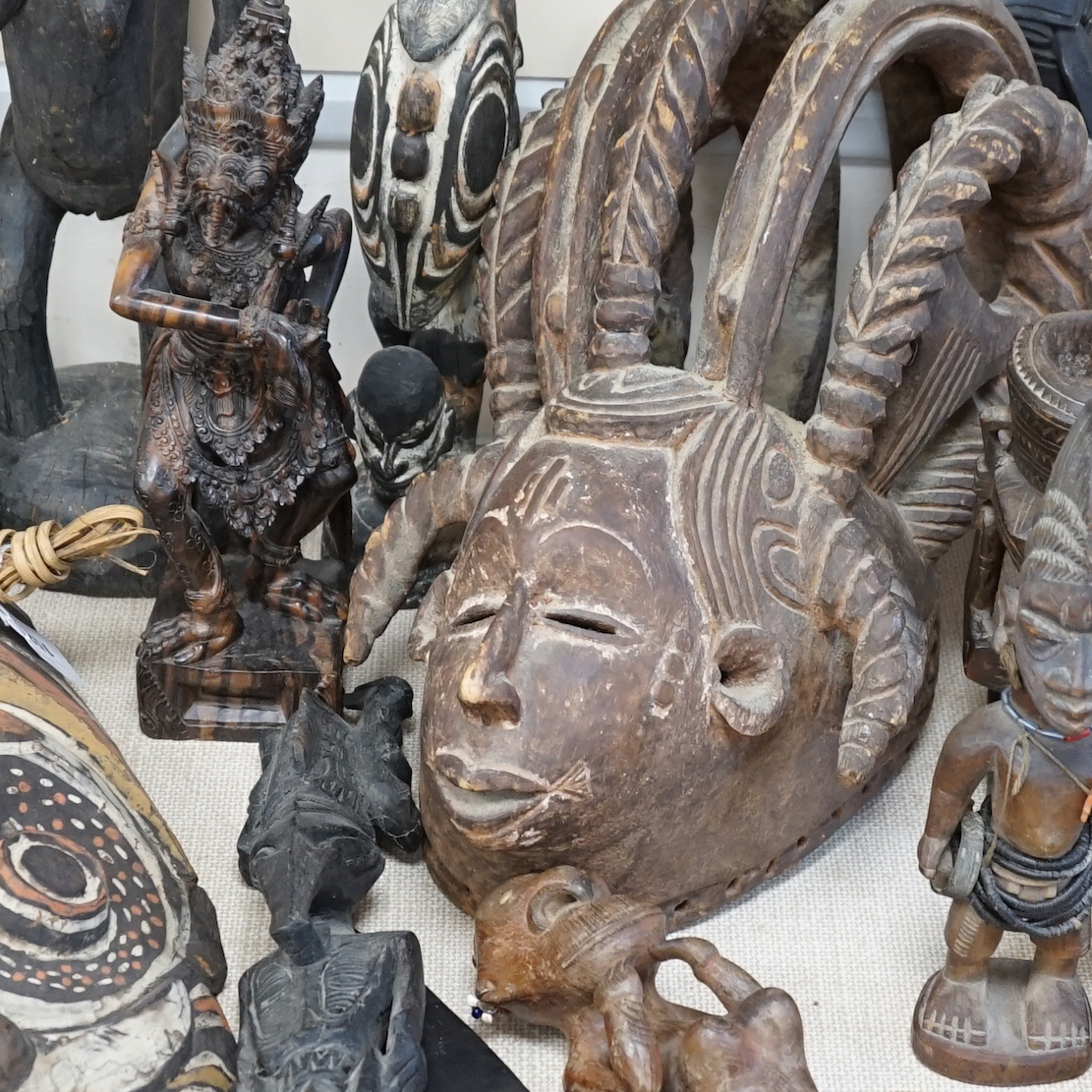 A collection of tribal carvings and masks mostly from Papa New Guinea, largest painted straw mask 86cm high